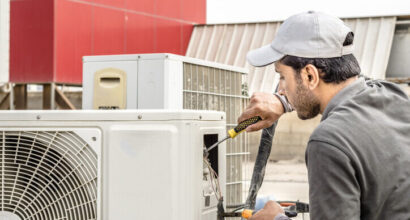 a professional an electrician repairman is repairing a heavy duty central air conditioner unite at the roof top  and wearing blue uniform